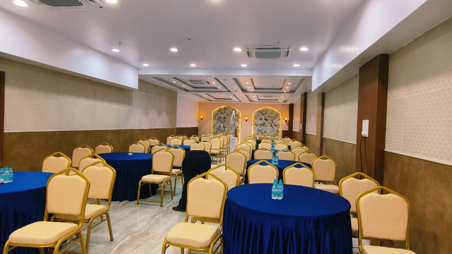 Hotel Mumbai House, Vashi banquet hall with round tables and chairs arranged for an event in a bright indoor setting.