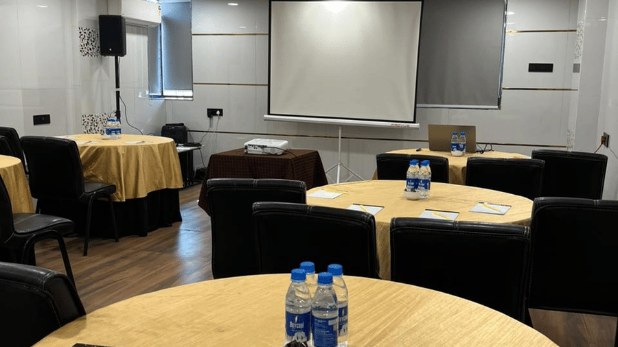 Round table banquet setup in a conference hall with yellow linens, stationery, and a projection screen in the background.