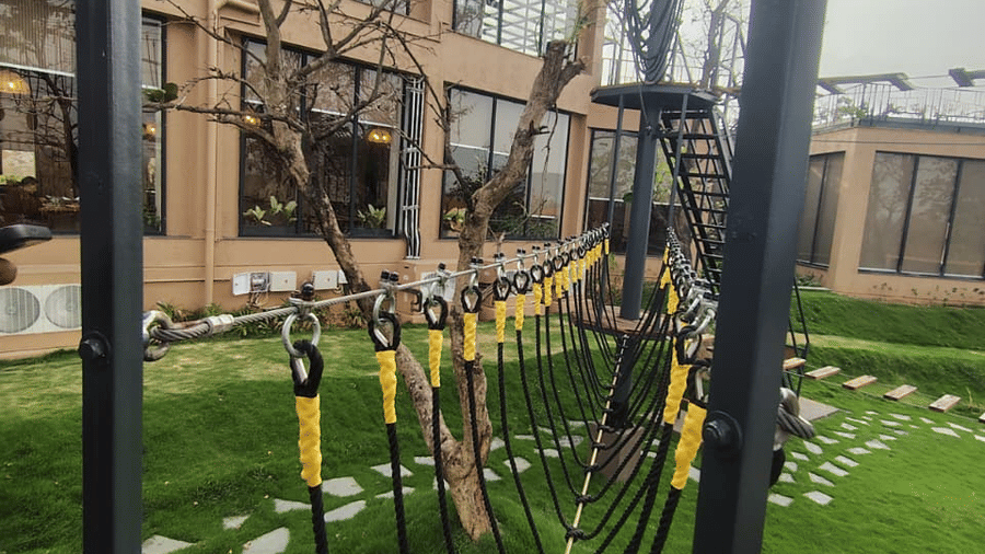 An outdoor activity area featuring suspended ropes and a climbing net structure over a grassy lawn at Hotel Sonar Bangla, Ajodhya Hills.