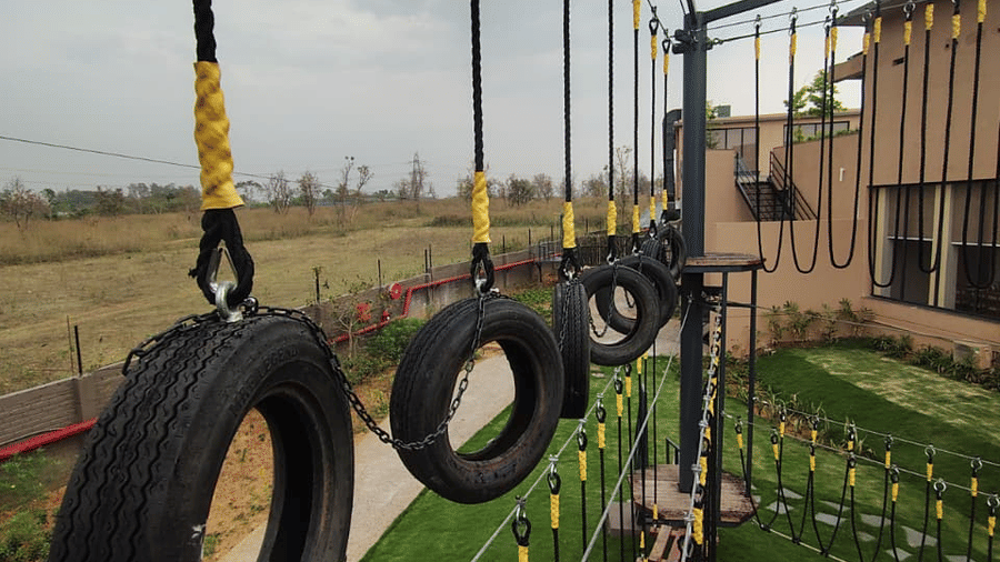 An outdoor obstacle course featuring a line of black tyres hanging vertically from ropes at Hotel Sonar Bangla, Ajodhya Hills.