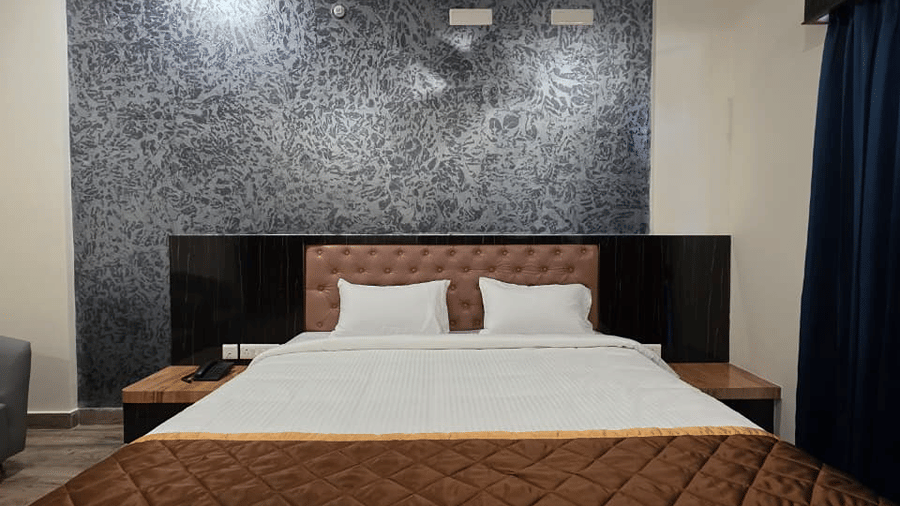 A bedroom with a king size bed, a ceiling fan above, and a dark textured wall panel behind the headboard.