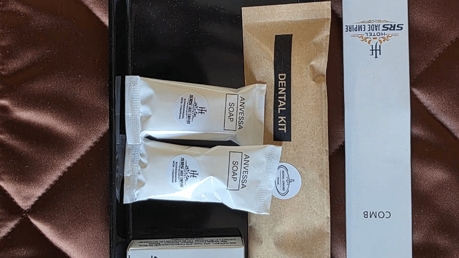 A tray of guest amenities placed on the bed, including toiletries arranged neatly for use.