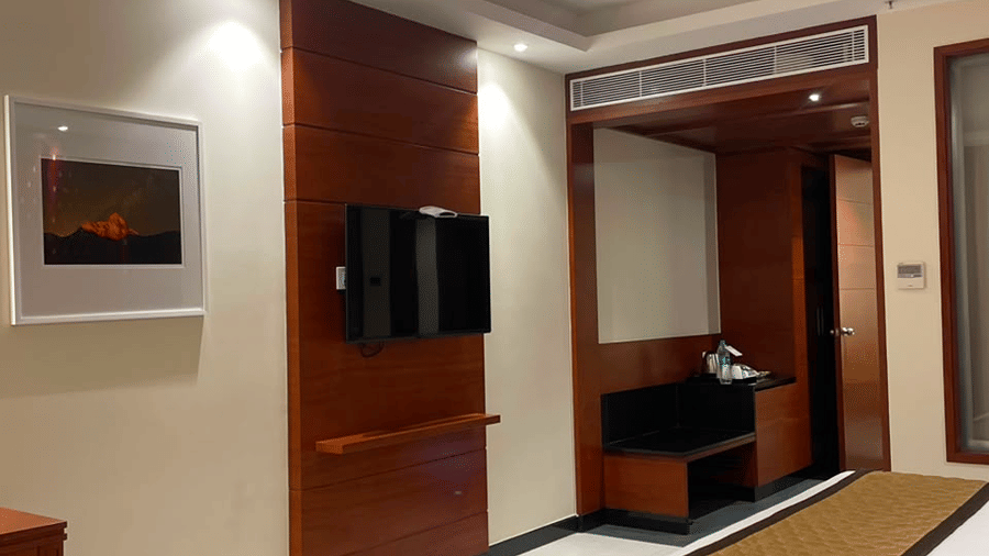 A room with a large bed, sheets, pillows, a television, and curtains. | MM Legacy, Kanchipuram