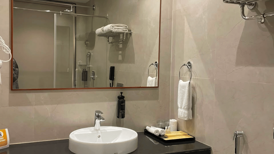 MM Legacy, Kanchipuram | A bathroom with a toilet seat, a sink, and other toileteries.