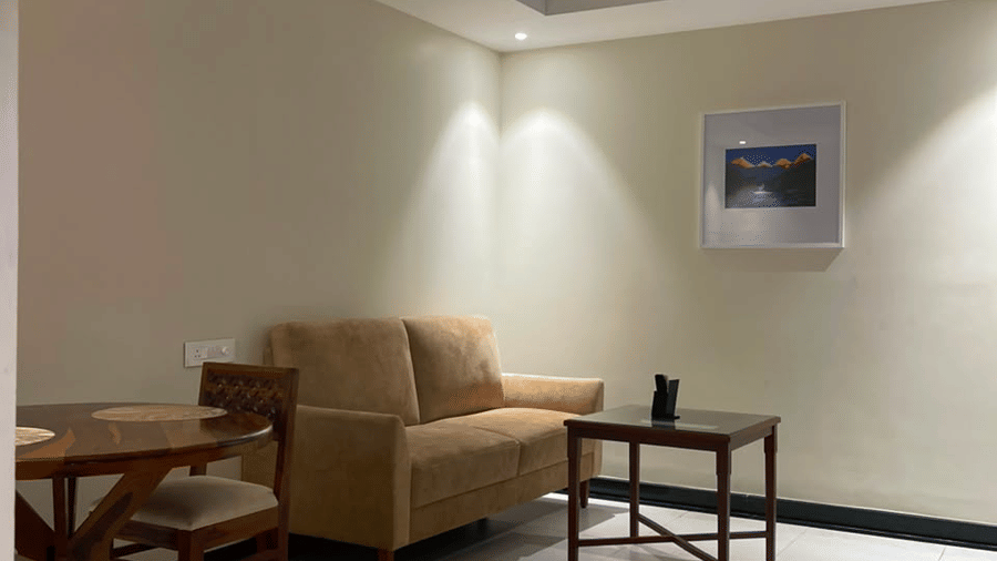 A seating area with a sofa, a table, chairs, and a wall mounted frame. | MM Legacy, Kanchipuram