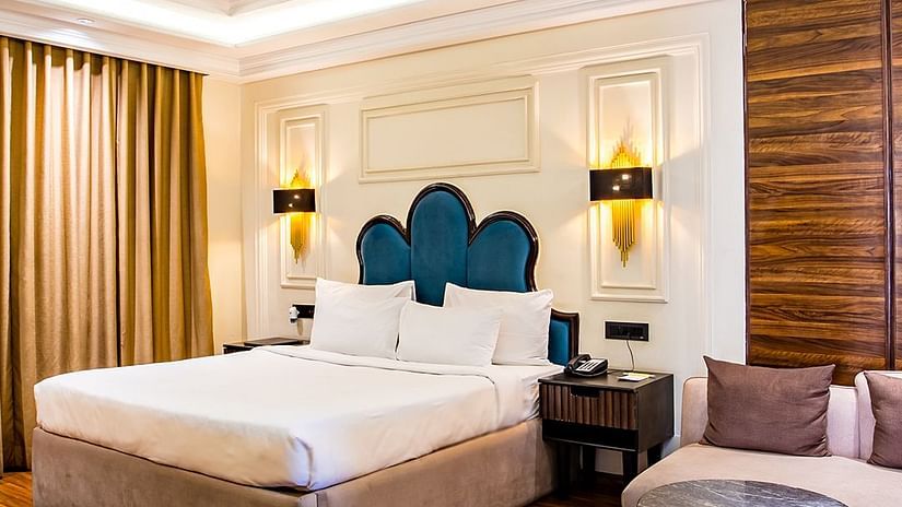 Luxurious hotel room with a king-sized bed and elegant decor with wooden panelled floors - Wedlock Greens Hotel & Resort, Dhanbad