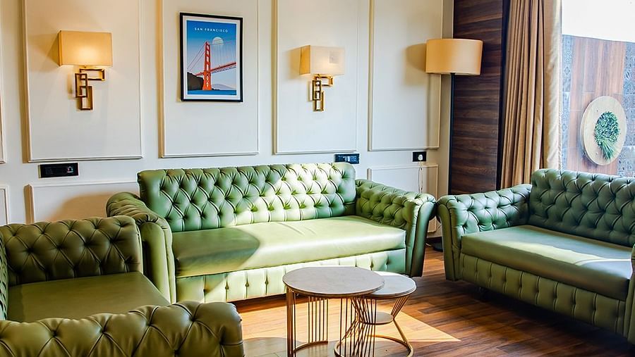 Spacious and luxurious living room with green sofa and wooden flooring - Wedlock Greens Hotel & Resort, Dhanbad