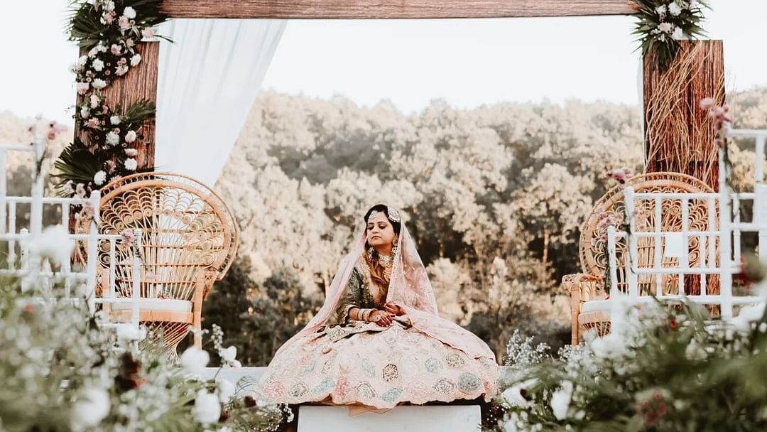 A photo shoot of a bride sitting on a lavish setup of the stage at The Sylvan Retreat, Dehradun.