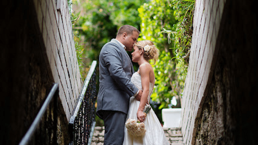 A couple standing in a narrow stone stairway tunnel, embracing each other under natural light | A Stone's Throw Away