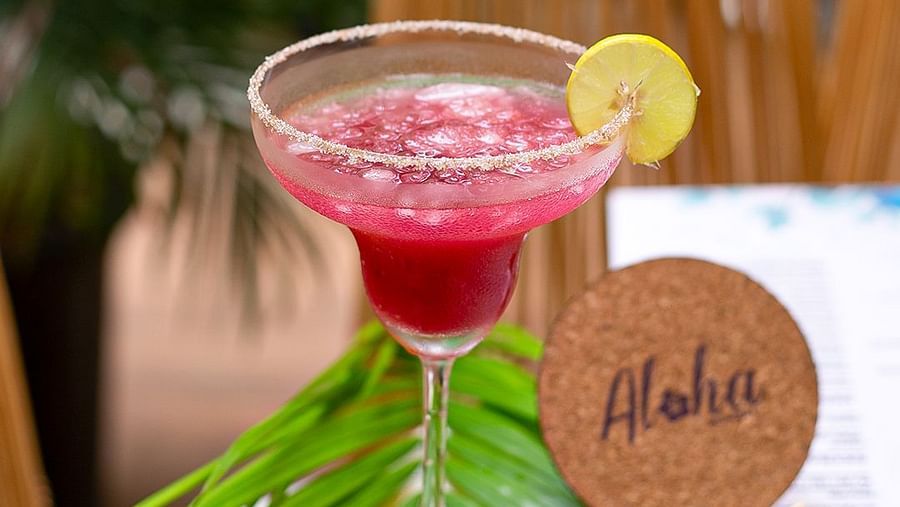 Pink margarita with lime and an Aloha coaster on a leafy table setting at Hotel Mumbai House Mindspace, Malad.