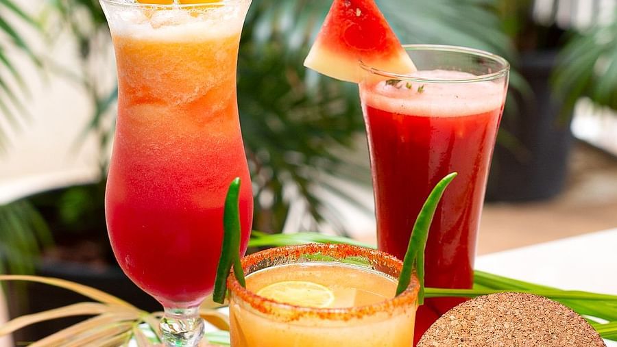 Three tropical cocktails with garnishes and an Aloha coaster at Hotel Mumbai House Mindspace, Malad.