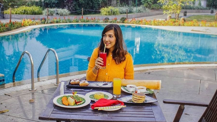 A Woman in a yellow dress dining by the pool - Rhythm Lonavala