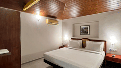 a double bed with side tables and lamps inside one of the rooms - Abad Harmonia, Kovalam
