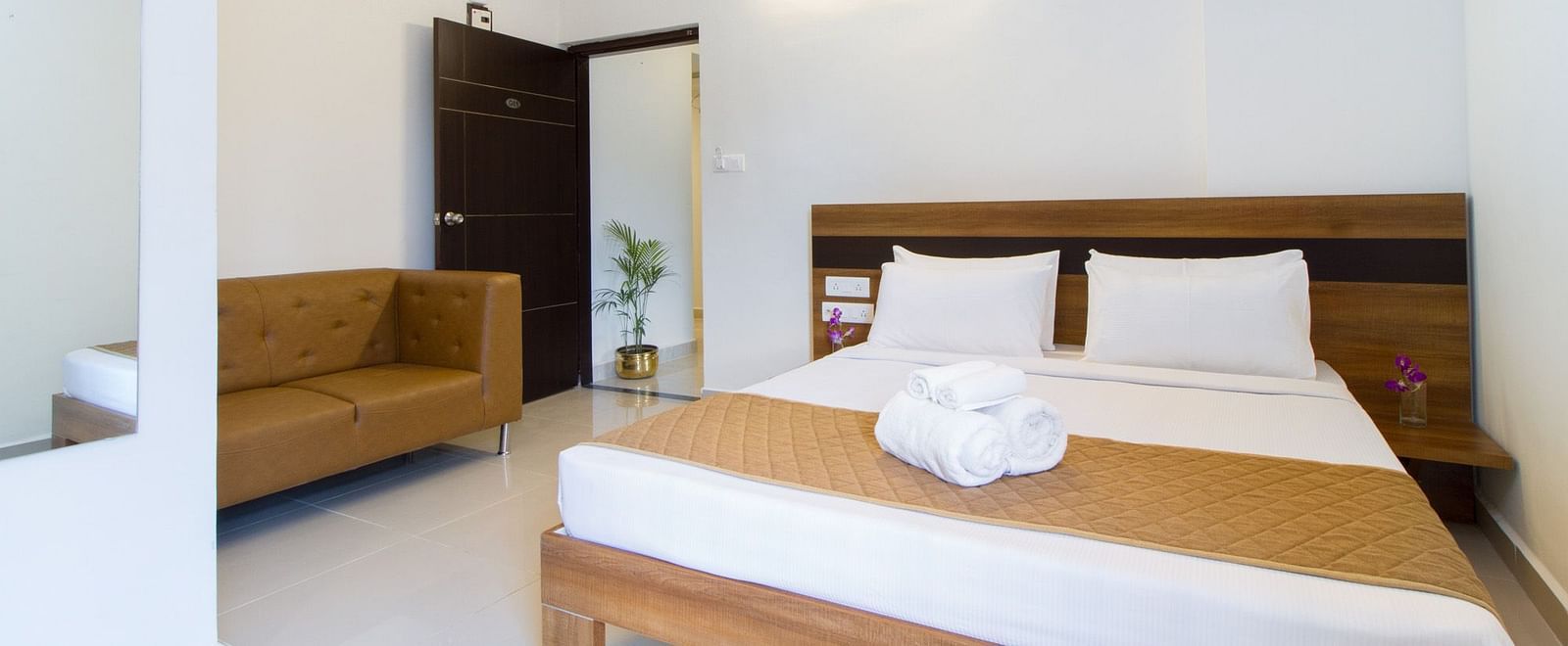 A hotel room including a double bed with bedding and an armchair at Sanctum Suites Whitefield, Bangalore.