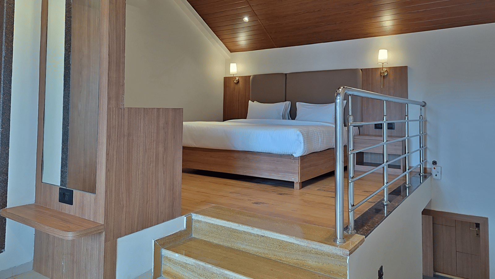 Bedroom with a double bed, wooden furnishings, loft area, and railing.