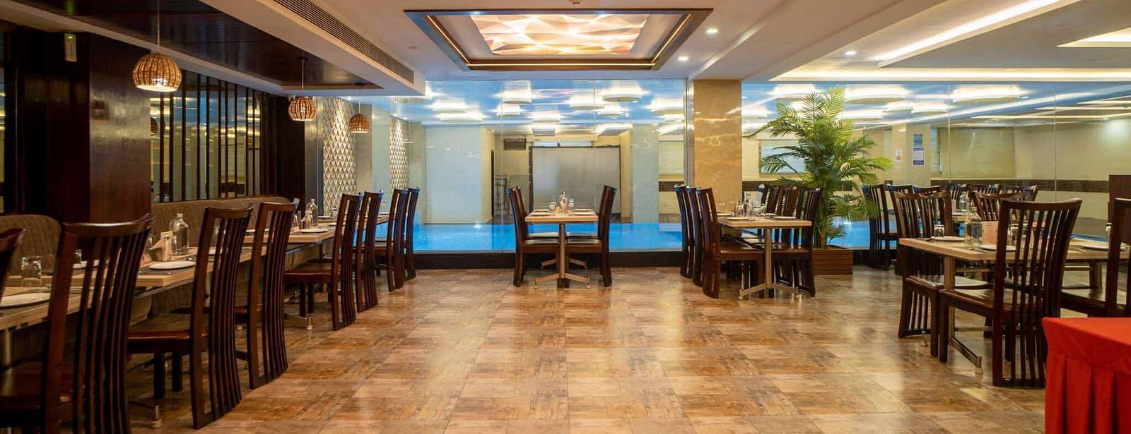 A spacious dining room at Mansha Hotel Regency with many tables and chairs, illuminated by warm lighting from the ceiling.
