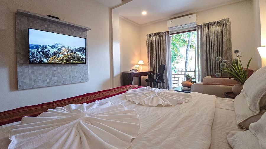 A spacious bedroom with a bed, towel art, and a wall-mounted flat-screen TV – The Verda de Miranda Resort.