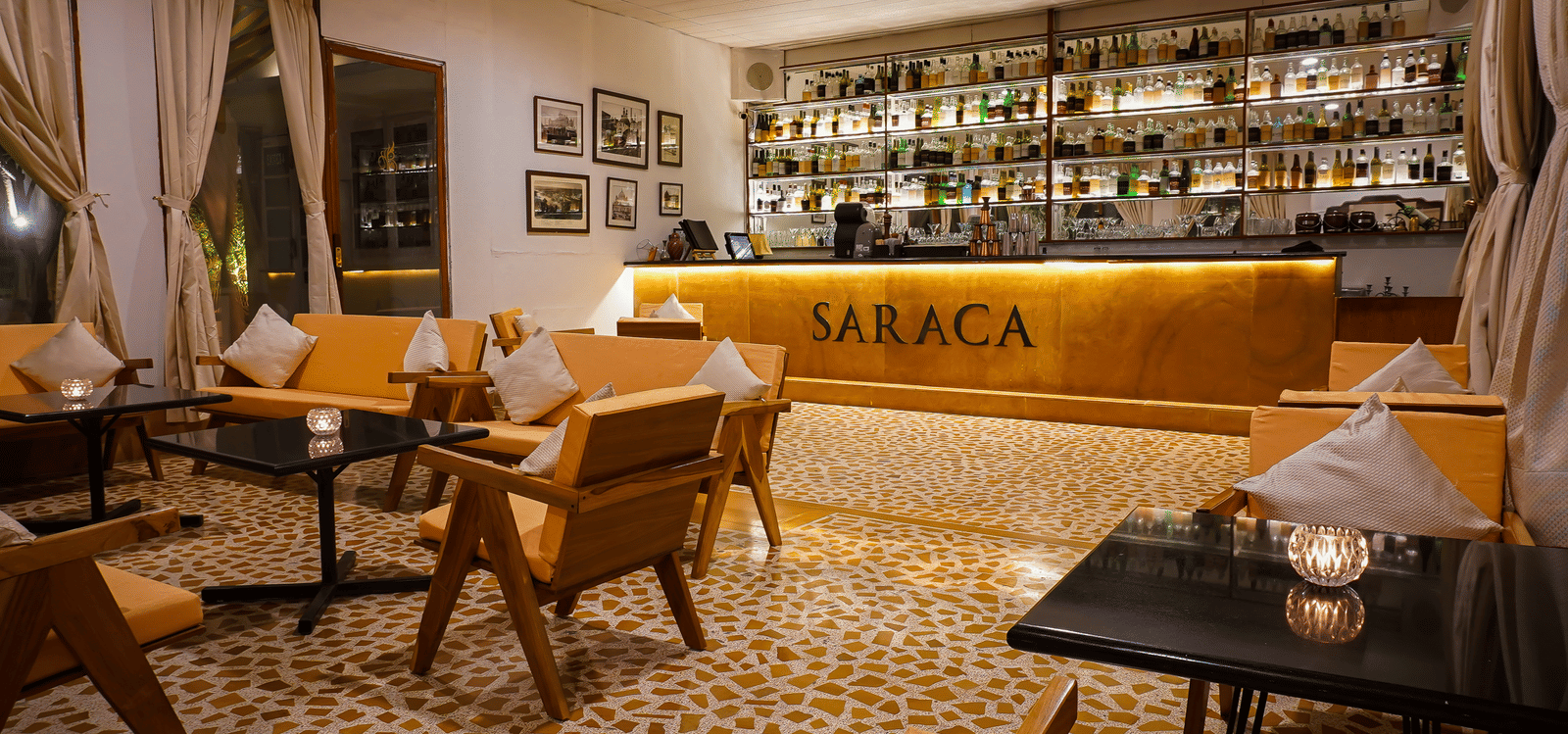 Interior of Saraca Rooftop Lounge at Saraca Hotel, Lucknow, featuring a well-lit bar, wooden seating, and a warm, contemporary ambience ideal for relaxed evening gatherings.