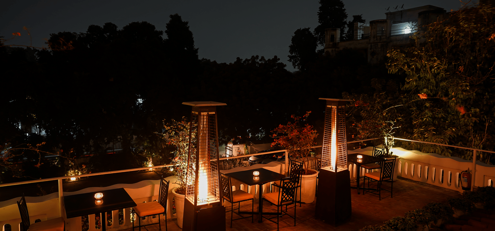 Outdoor night view of Saraca Rooftop Lounge at Saraca Hotel, Lucknow, showcasing cosy seating, ambient lighting, and serene surroundings for an intimate open-air experience.