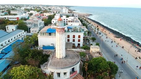 An aerial view of Pondicherry with buildings next to a beach and people walking.