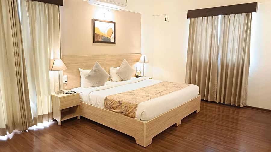 Plush bed on a well-furnished floor under warm lighting with two lamps on the nightstands on both sides of the bed inside premium studio at Starlit Suites, Shirdi