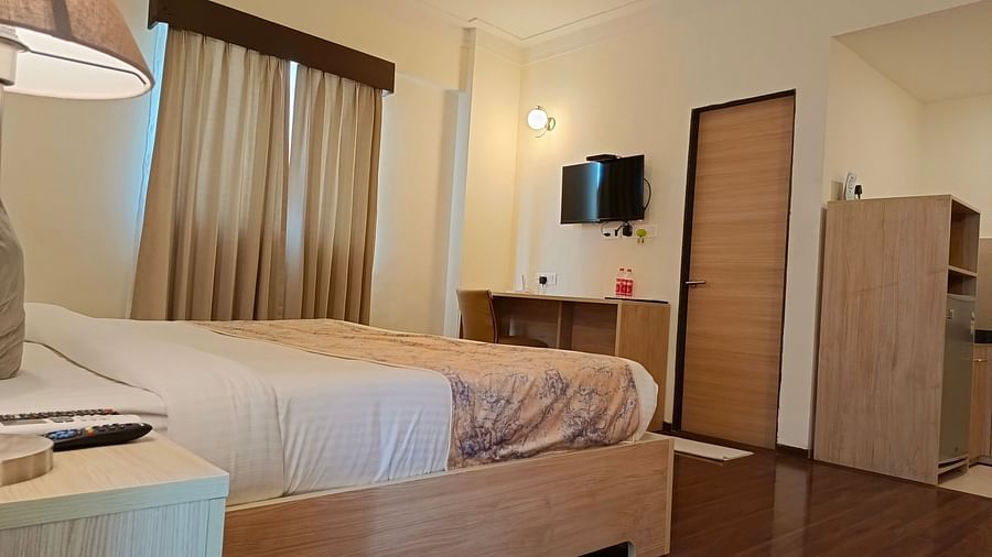 Plush bed facing the TV mounted on the wall inside premium studio - Starlit Suites, Shirdi