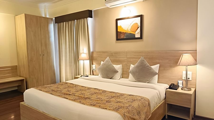 Plush bed with a couple of lamps lit on both sides on the nightstands inside warmly lit premium studio at Starlit Suites, Shirdi