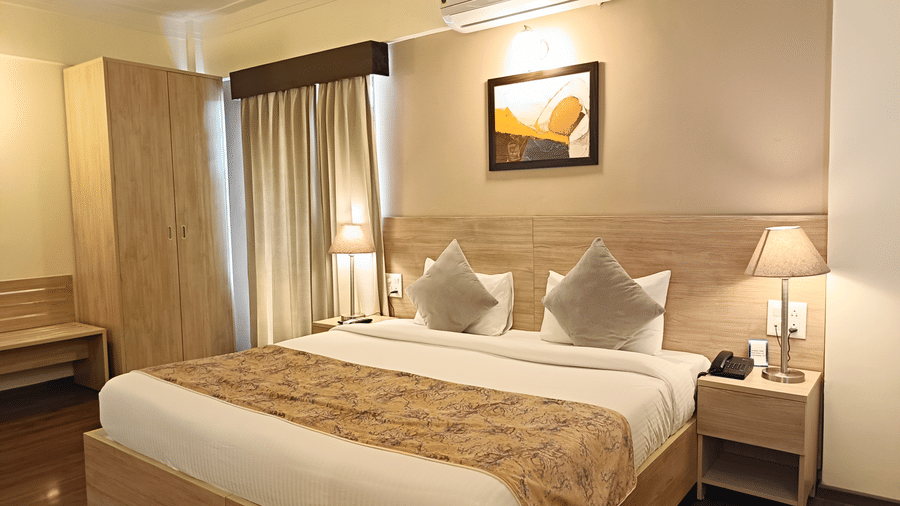 A plush bed with lamps lit on both sides on the nightstands inside a warmly lit Premium Room at Starlit Suites, Shirdi.