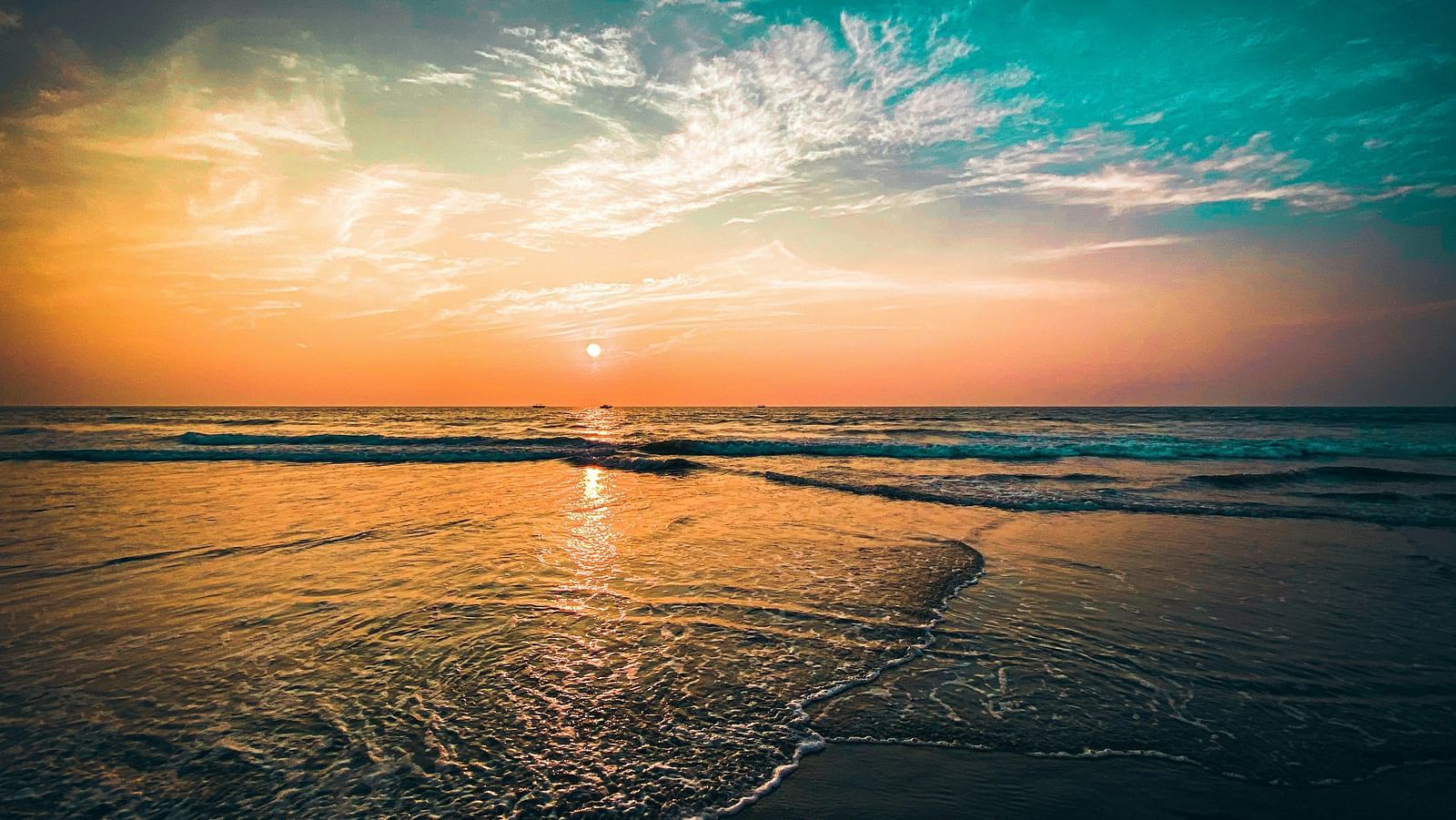 an overview of a beach in goa with the sun setting while creating different hues in the sky