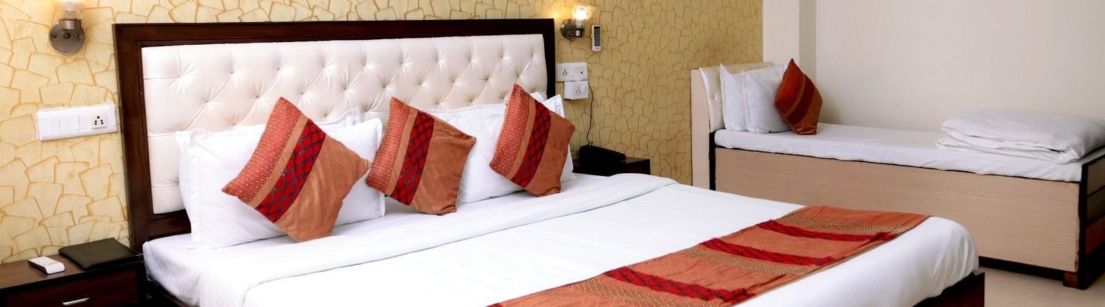 A luxurious hotel room with a king-size bed, golden accent wallpaper, warm lighting, and a modern aesthetic - Hotel Diamond Inn, Chandigarh