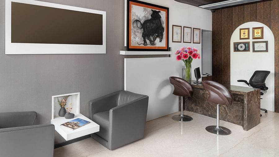 An elegant reception room at The Atara, Gurugram is furnished with comfortable seating, a large display screen, framed artwork, and a stylish full-length mirror, exuding a sophisticated feel