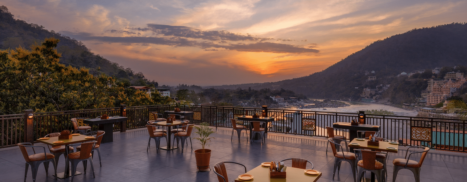 Terrace restaurant seating with sunset hues and surrounding mountain views.