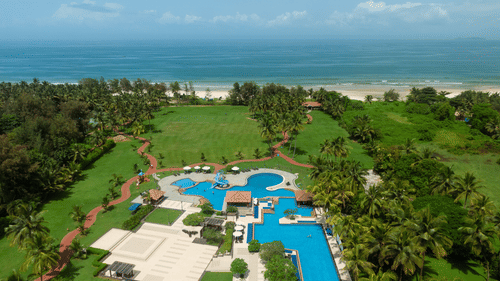 an aerial view of the kenilworth resort and spa in goa with vast blue ocean at the far end.