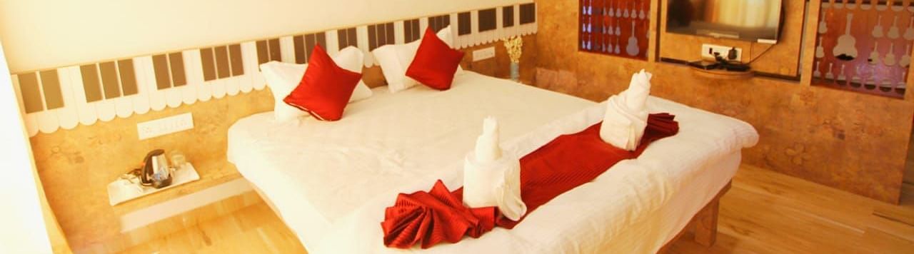 A diagonal view of the room featuring a spacious bed with towels folded in different shapes on it. There is a wooden table with a wall-mounted television at SeaFort Beach Resort