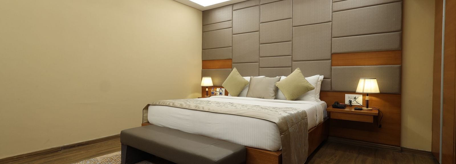 Hotel room interior with a bed, a bench, and a fan, a guest accommodation at Rang Lords Inn Bharuch