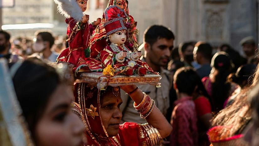 A huge procession celebrating a festival and a woman can be seen holding idols of Gods and Goddess over her head.