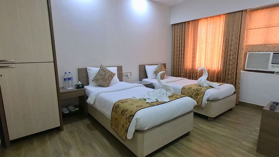 A view of neatly made twin beds and a wardrobe in a well-lit room