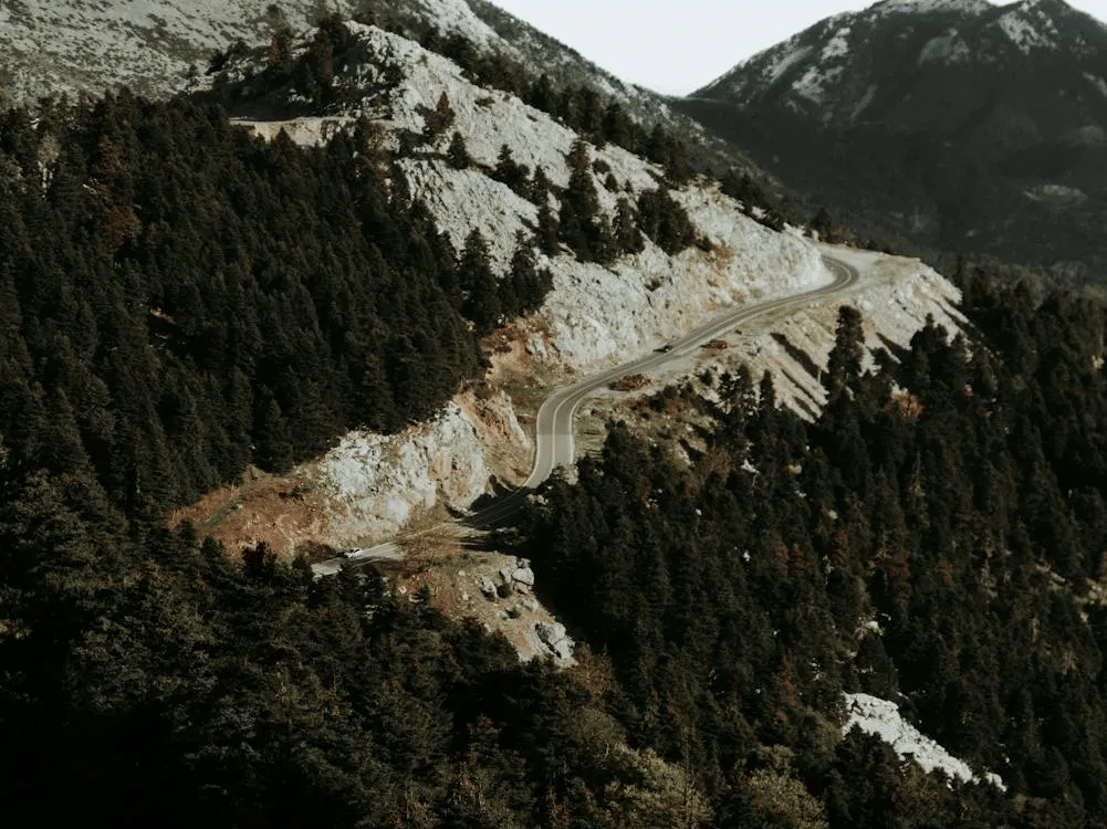 View of a rocky, forested mountainside against cloudy sky.