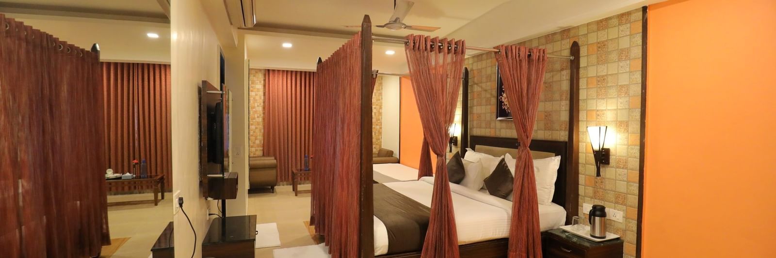 A spacious suite at Krushnai Resort with a four-poster bed, mirror, and a seating area.