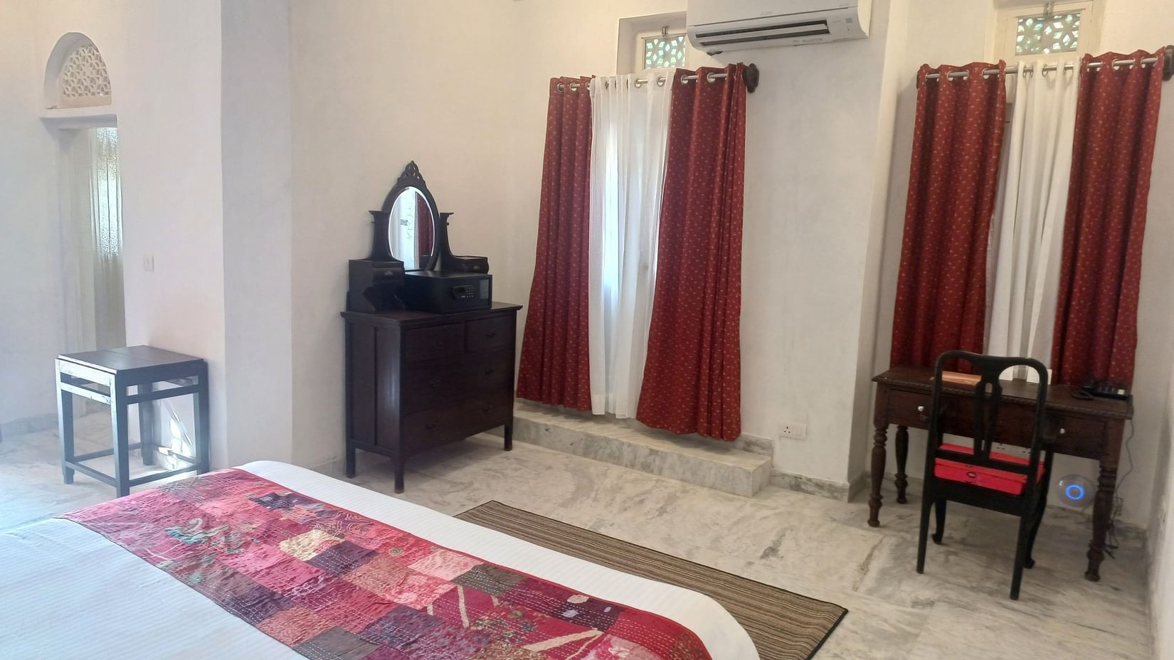 Spacious bedroom featuring dark wood furniture, air conditioning, burgundy curtains, and marble flooring at Neemrana Fort-Palace - 15th Century, Delhi-Jaipur Highway.