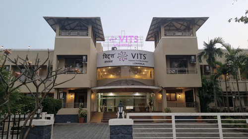 A facade image of VITS Lonavala with warm golden lighting showcasing the entry gate and greenery around