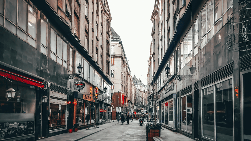 An overview of an empty street market with many shops in view and a few people walking.
