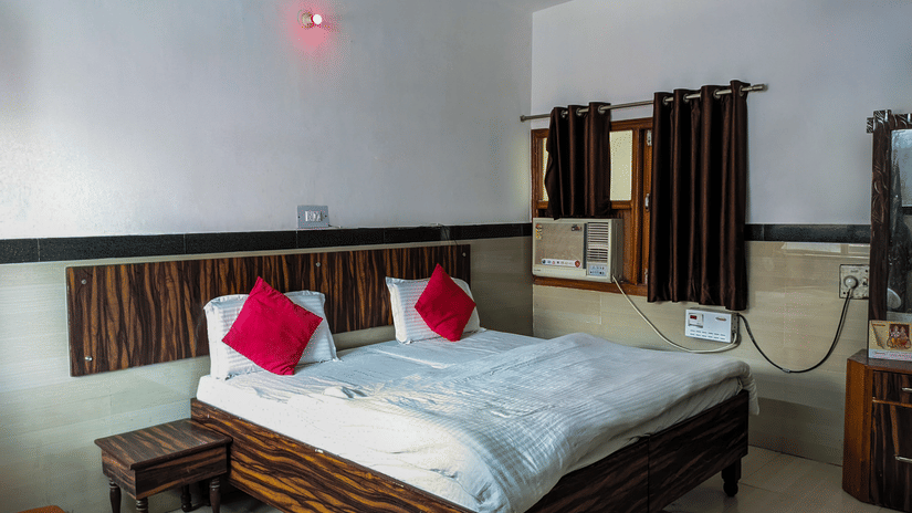 Double bed in the room with pillows and cushions and a nightstand - Hotel Goverdhan, Agra