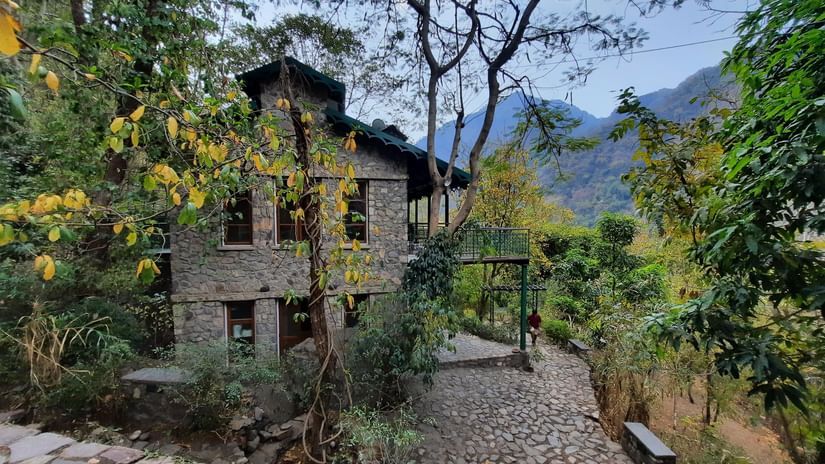 Facade view of Glasshouse on the Ganges amidst the nature with mountains and clear blue sky in the background.