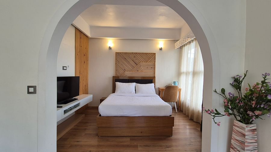 A hallway leading to a bedroom with a white bed, interior setting - Clarks Exotica Resort, Near Mukhteshwar.