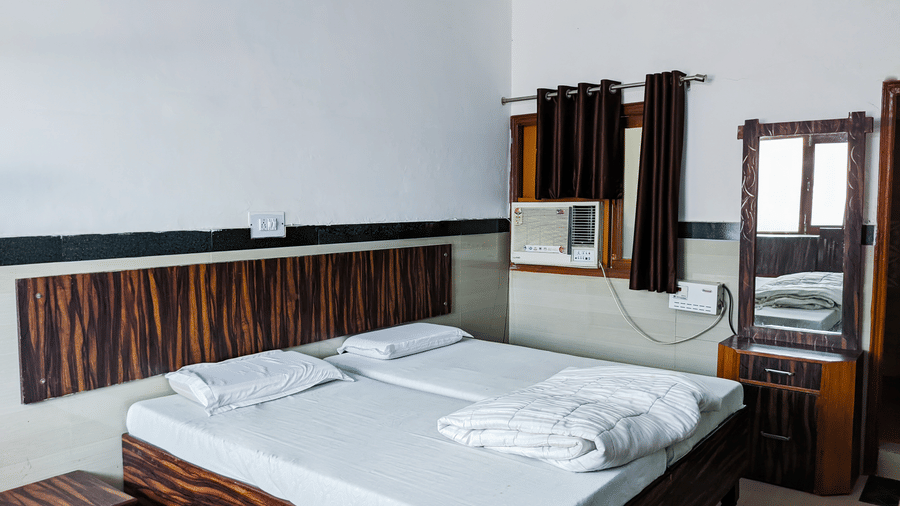 A twin bed with a couple of pillows with the room featuring mirror and air conditioner - Hotel Goverdhan, Agra