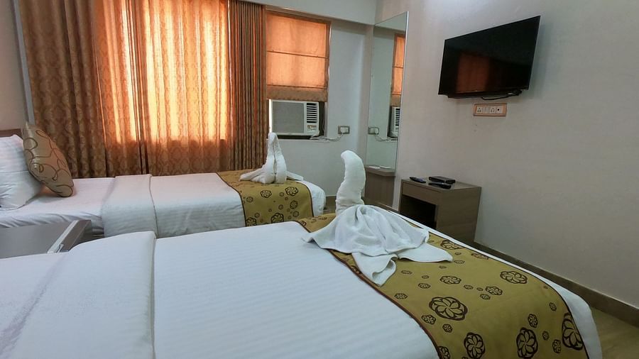 A side view of decorated twin beds in a bedroom with a TV on the wall