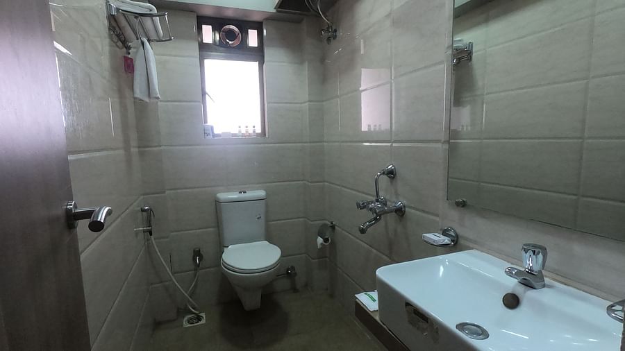 A view of the bathroom with a wash basin, western commode and a mirror