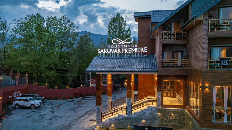 Entrance façade of Mountnoor Sarovar Premiere, Pahalgam surrounded by lush greenery and mountain views.