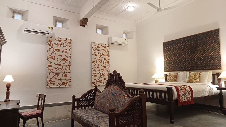 Traditional fort palace bedroom with white walls, dark wooden furniture, decorative wall panels, and period-style seating area.